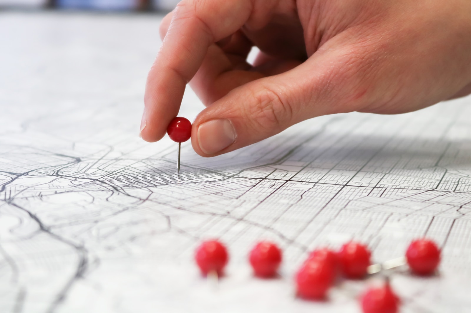 close-up photo of a hand placing a red topped pin into a map